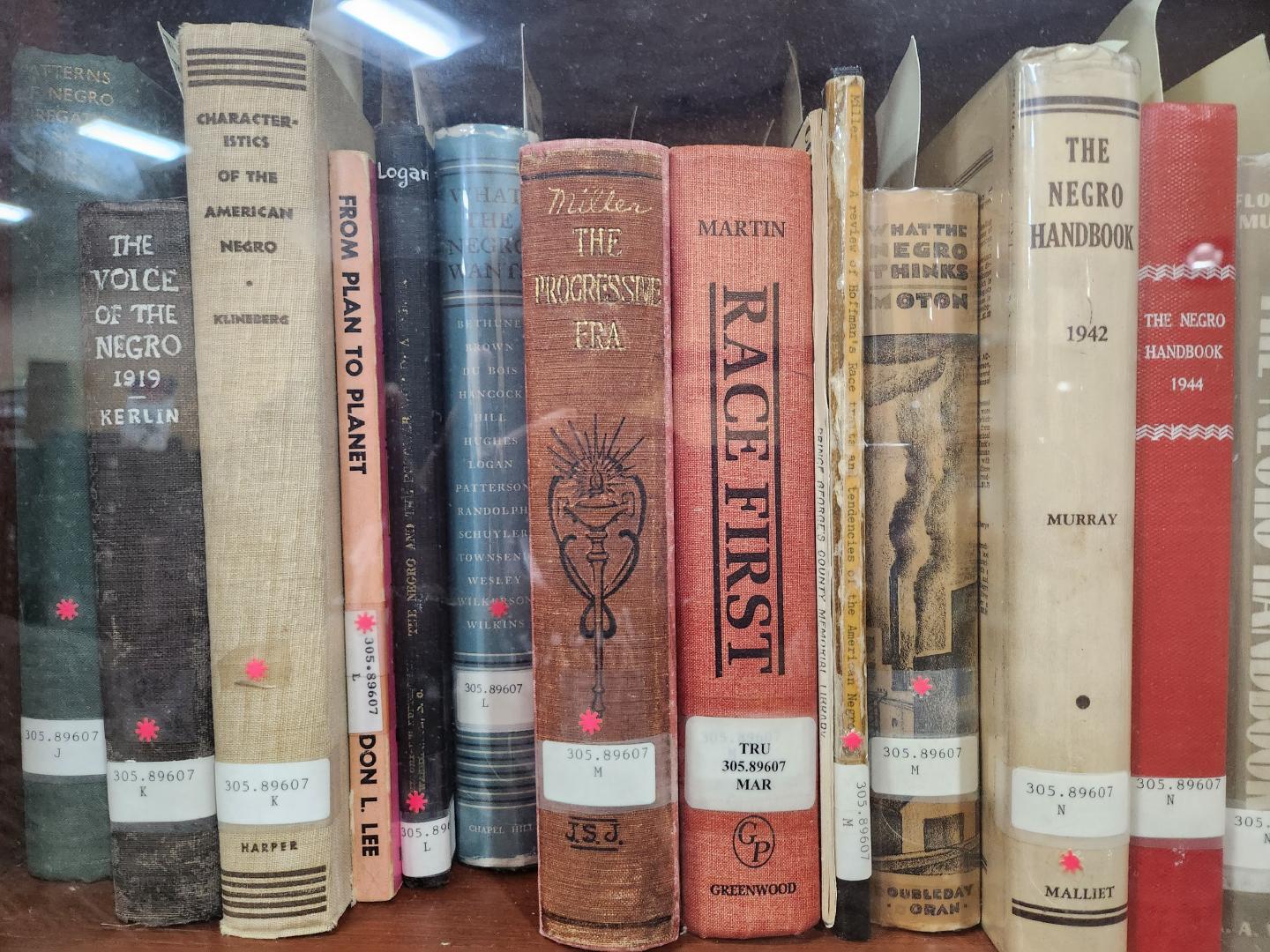 Shows several books on shelf such as the Negro Handbook and Race First