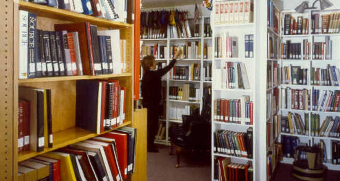 Shows woman picking a book from collection of books